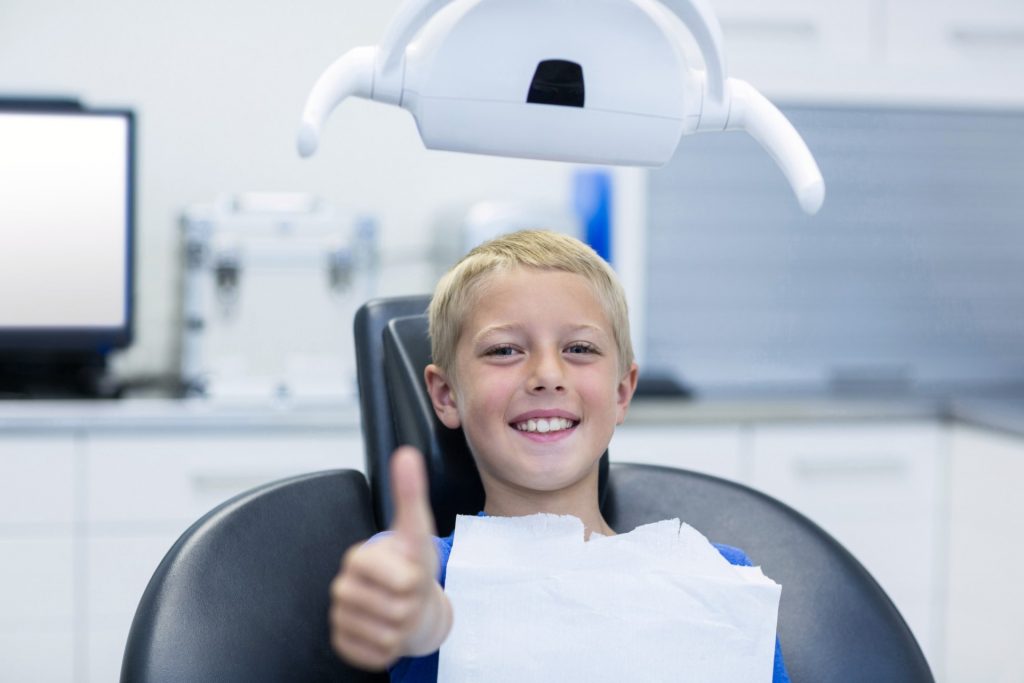 Smiling young patient sitting on dentist chair in dental clinic